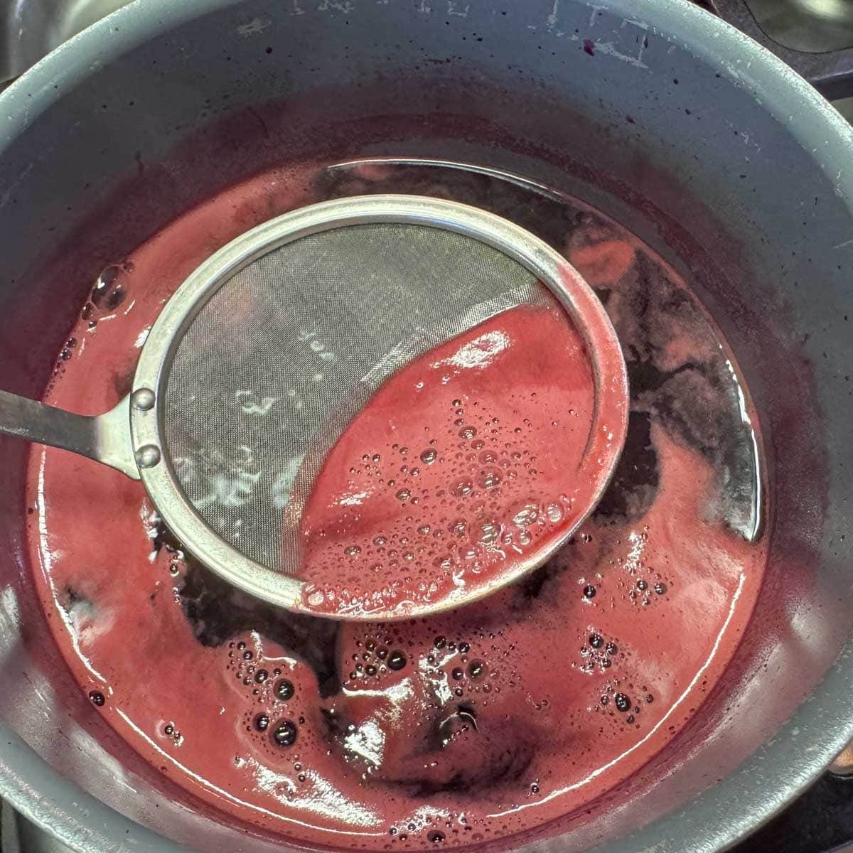 skimming pomegranate syrup to remove foam.