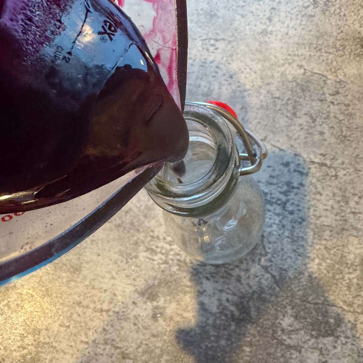 pouring pomegranate syrup into flip-top bottle.