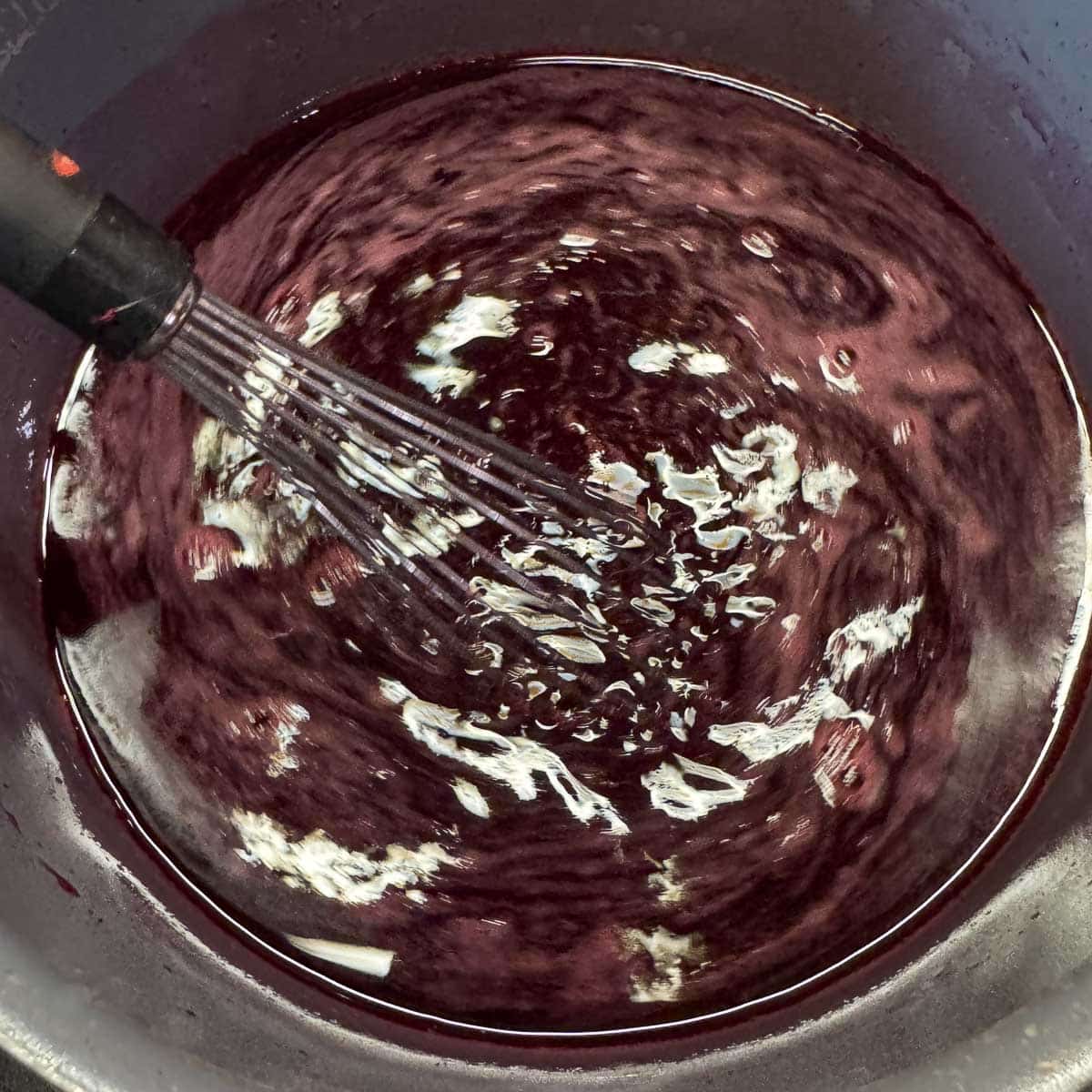 whisking pomegranate juice in a pot.