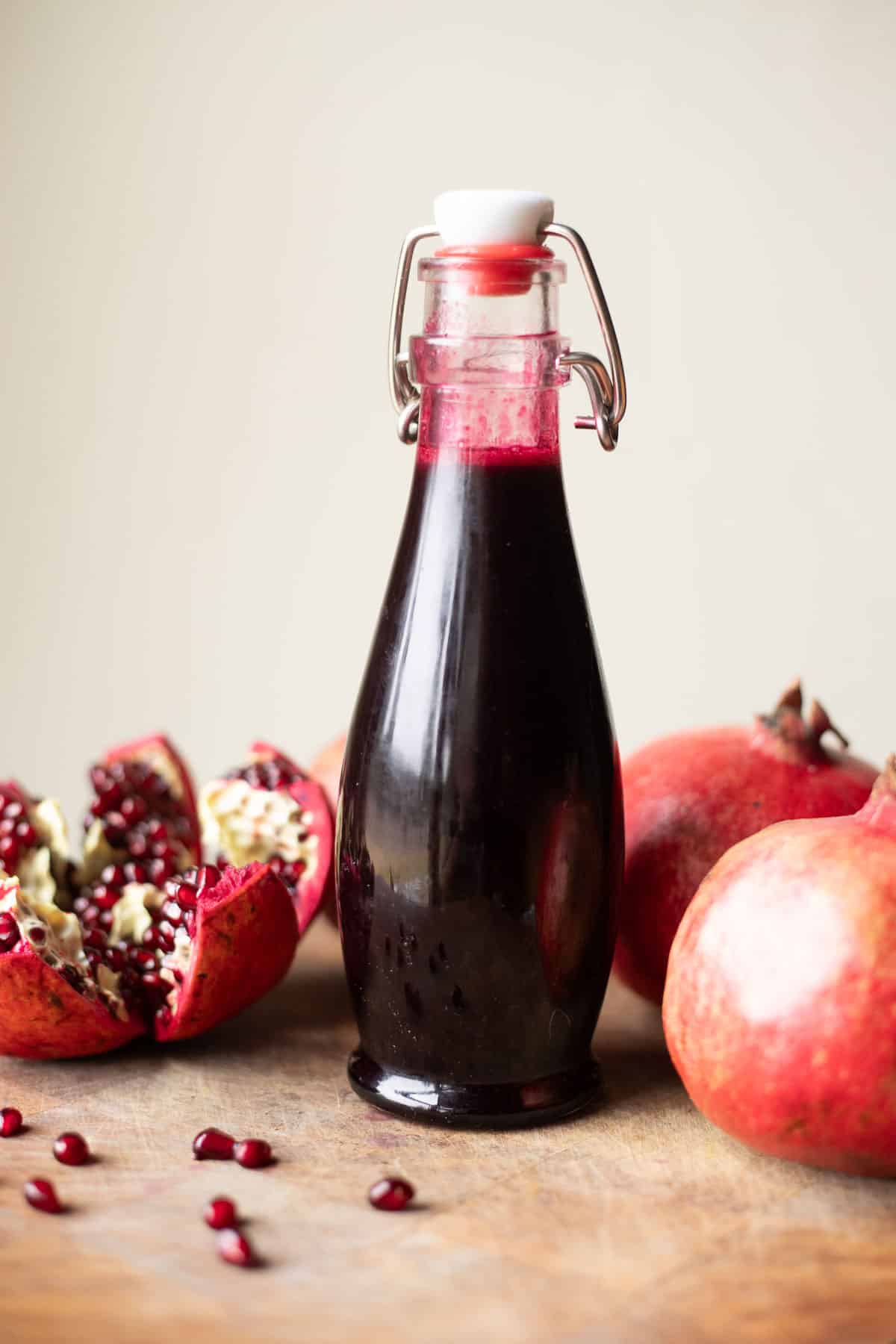 a jar of pomegranate syrup with fresh pomegranates around it.