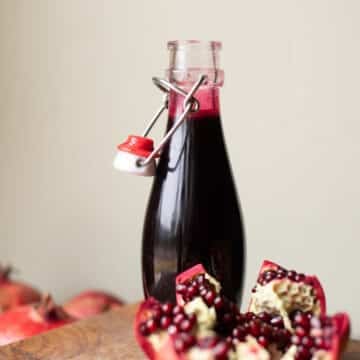 pomegranate syrup in a bottle with pomegranates around it.