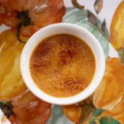 pumpkin creme brulee in a white dish with a pumpkin background
