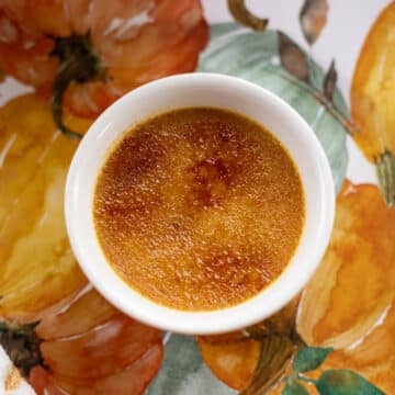 pumpkin creme brulee in a white dish with a pumpkin background