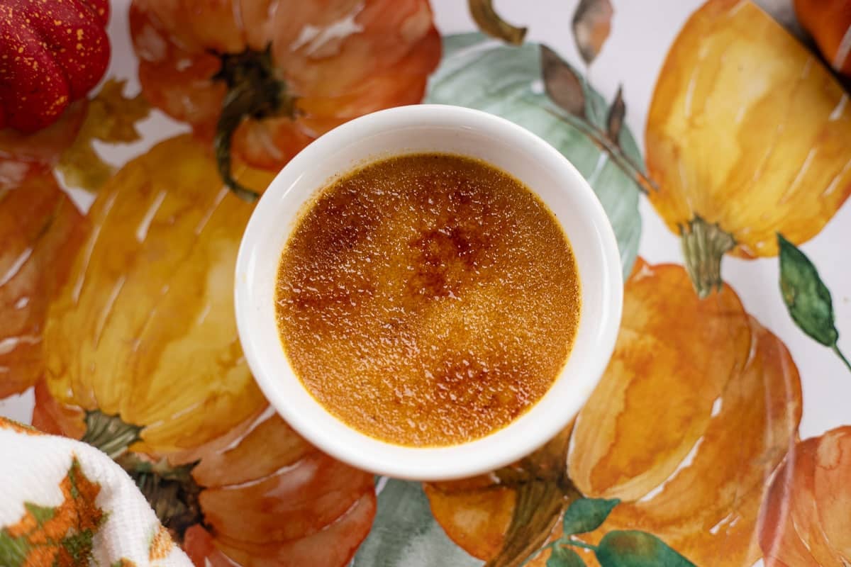 pumpkin creme brulee in a white dish with a pumpkin background .