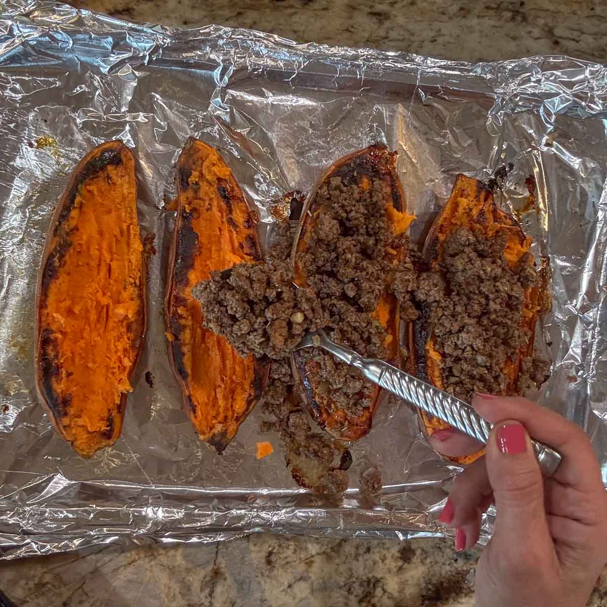 adding ground lamb to roasted sweet potatoes.