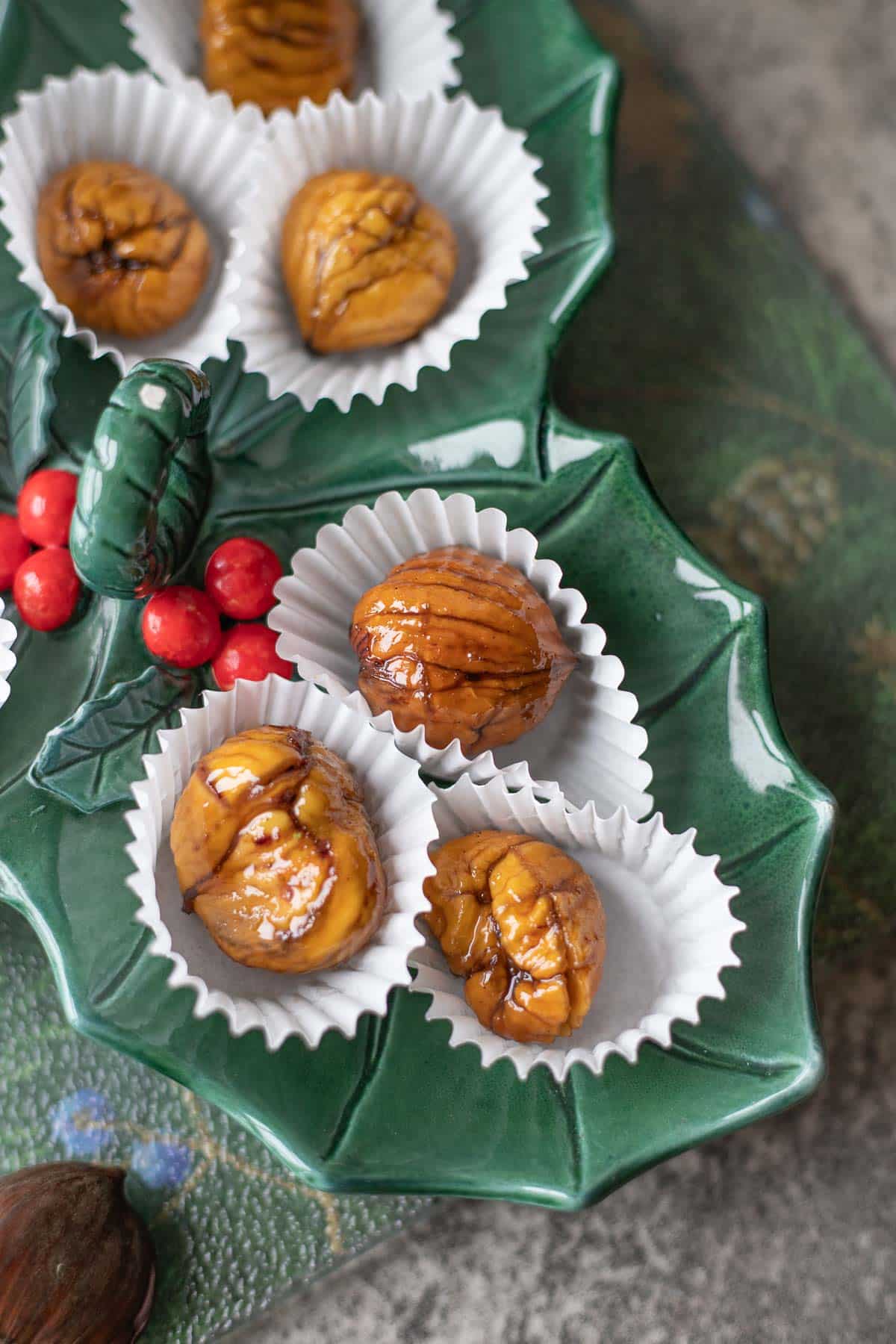 marron glacé in paper cups on a green holiday plate.