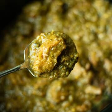 a spoon of crock pot chile verde over a pot of chile verde.