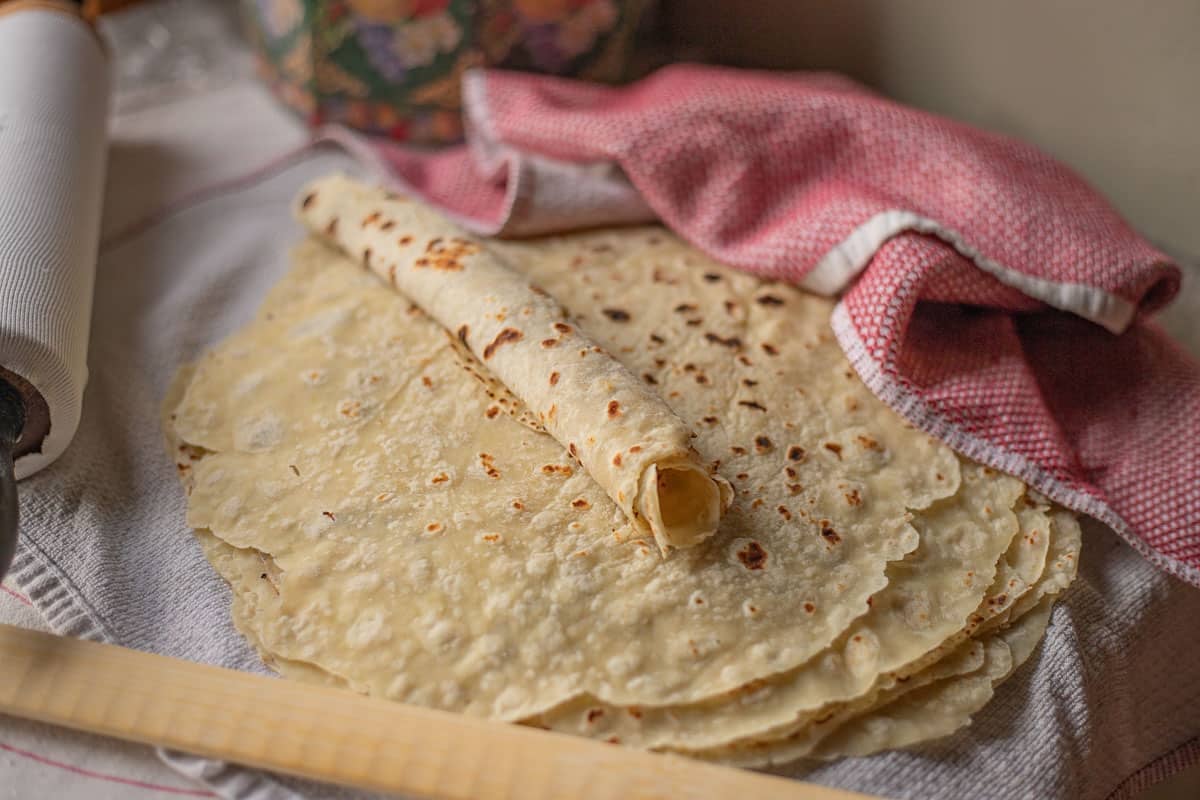 lefse stacked on a red dishtowel.