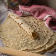 a stack of lefse with one rolled up on top of the stack.