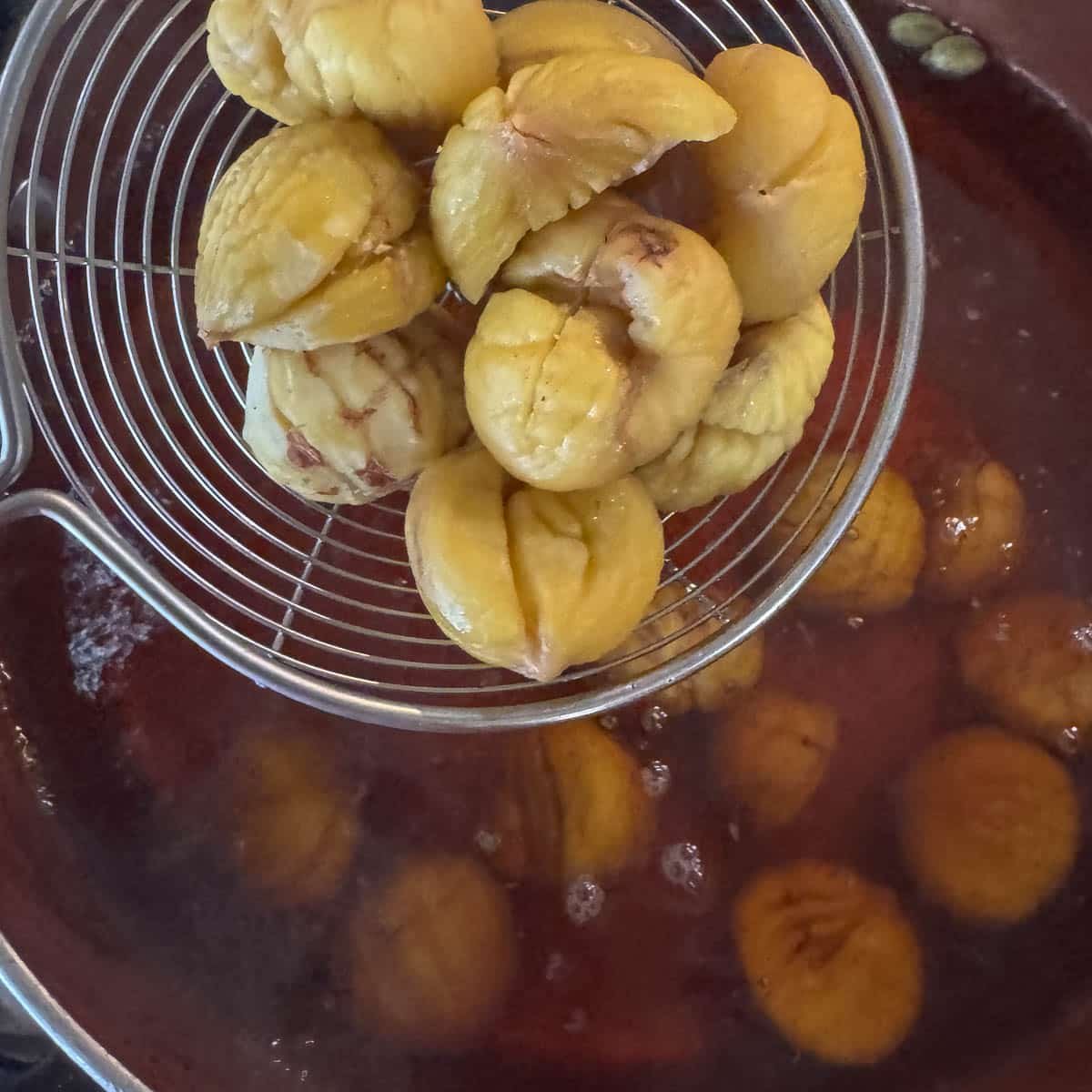 adding chestnuts to syrup in a pan.