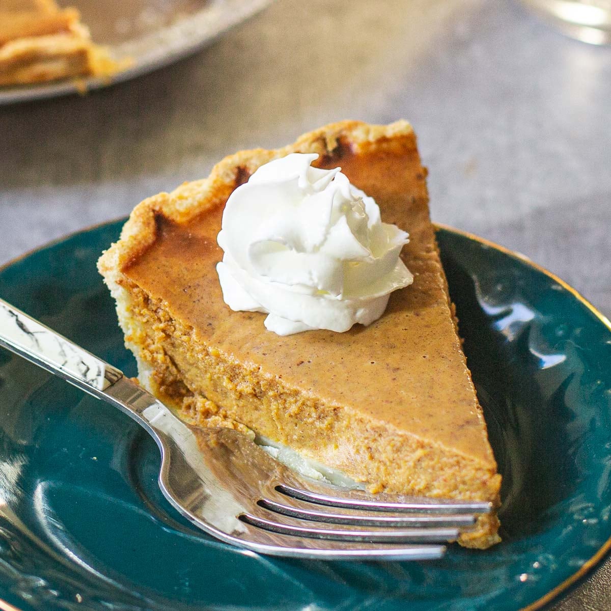 pumpkin pie with condensed milk on plate with whipped cream and fork.