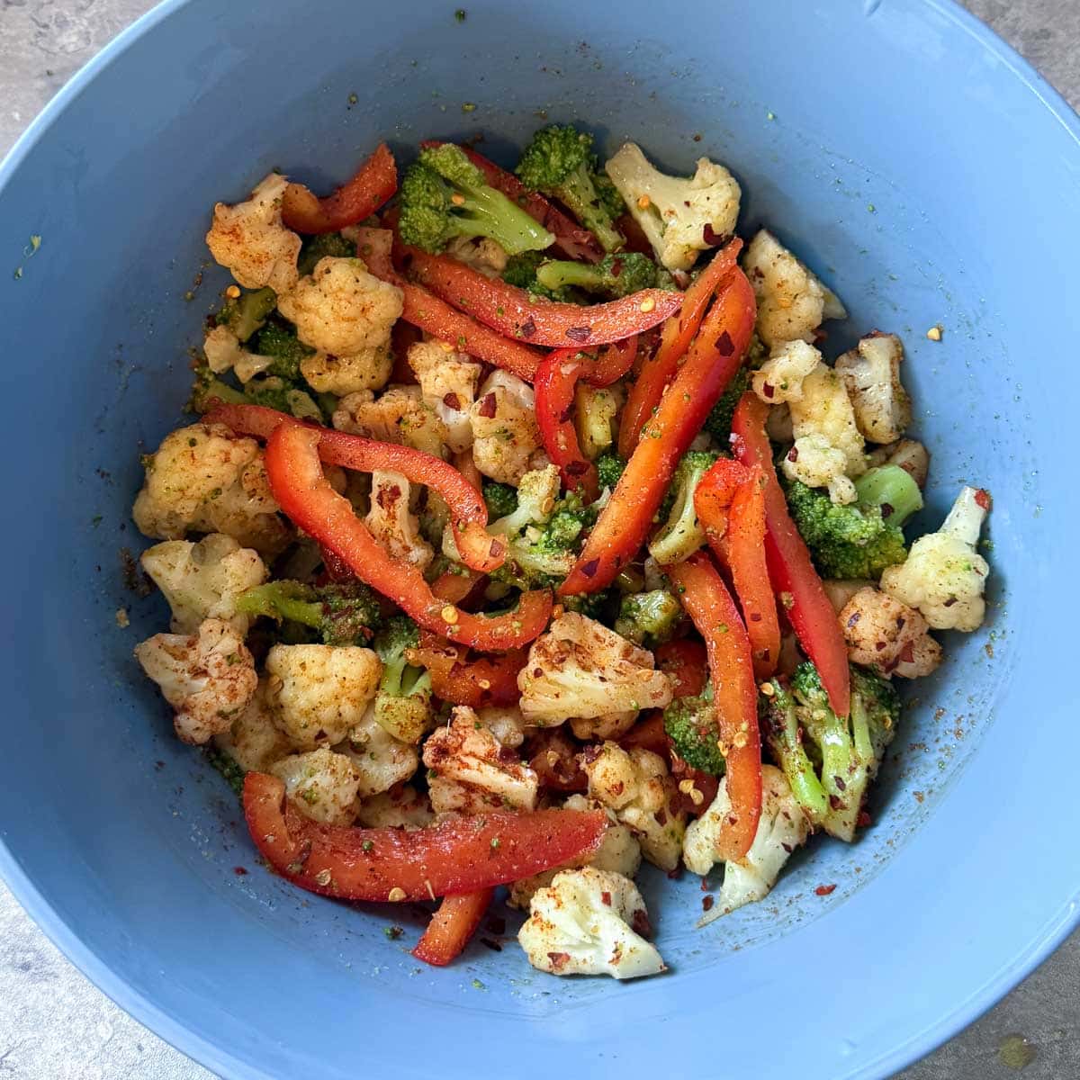 veggies in bowl after tossing with oil and seasonings.