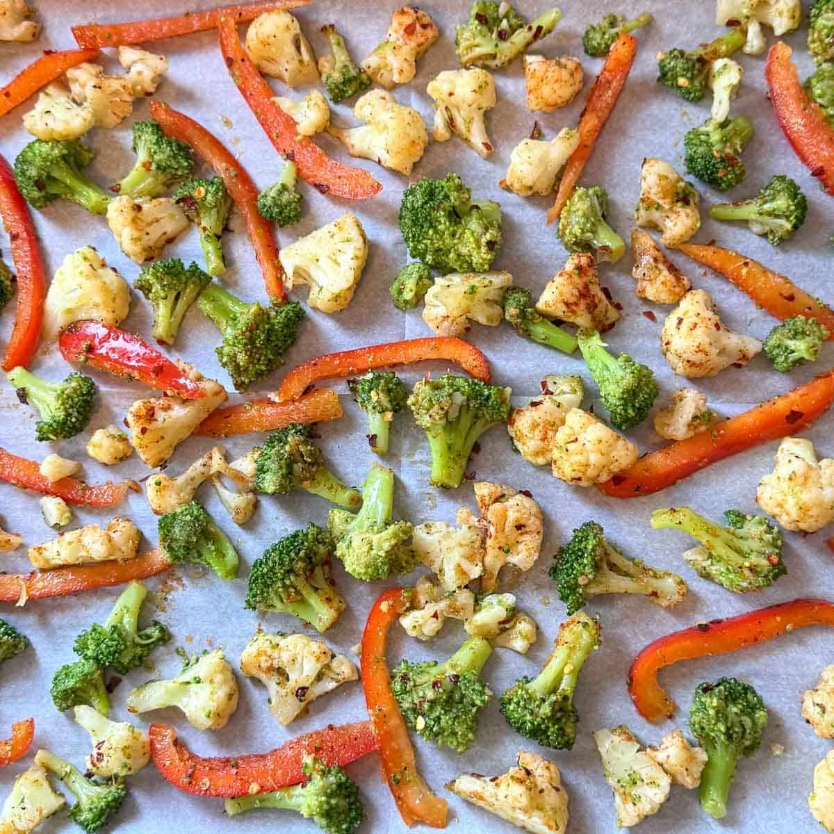 broccoli, cauliflower, and red peppers on baking sheet.