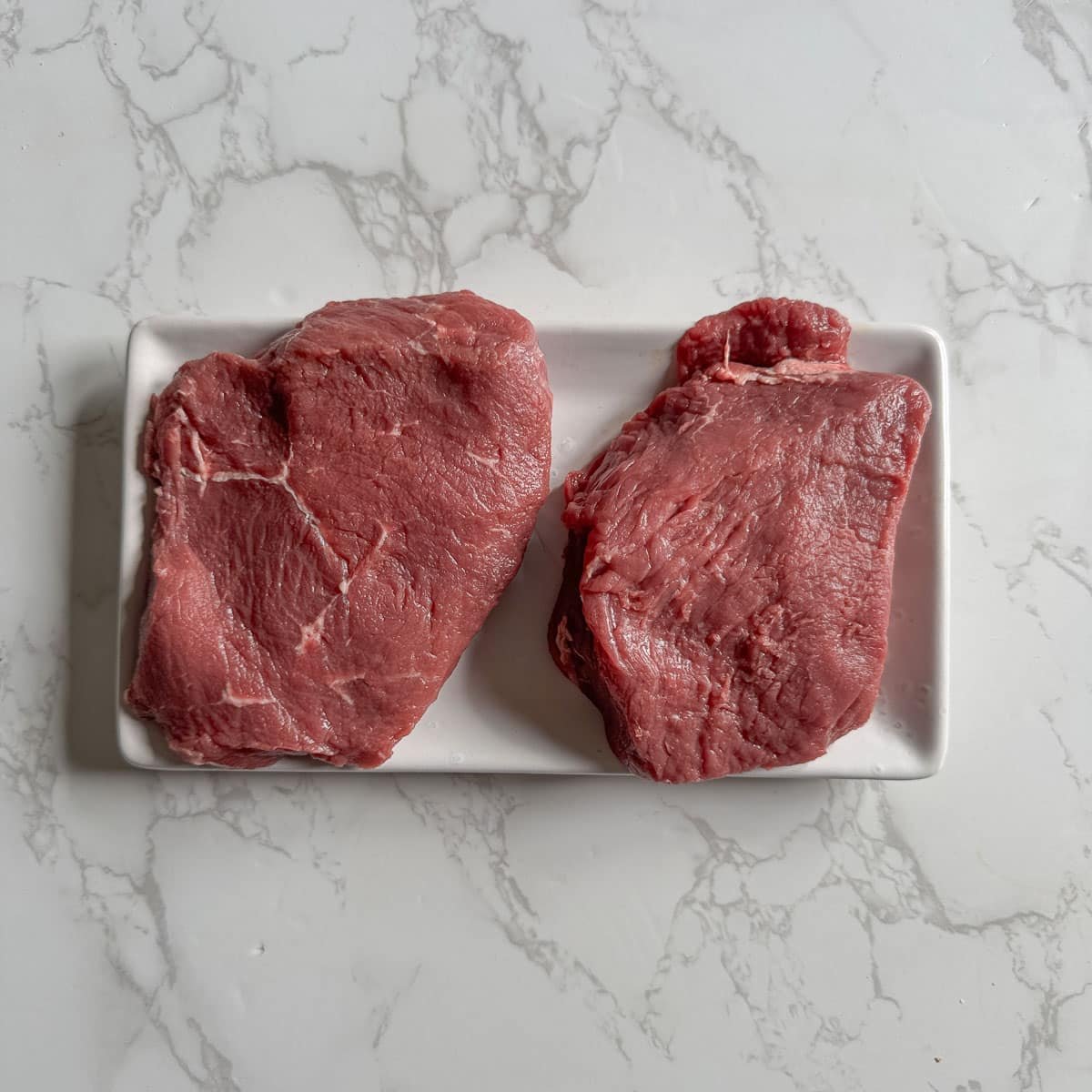 raw sirloin steaks on plate.