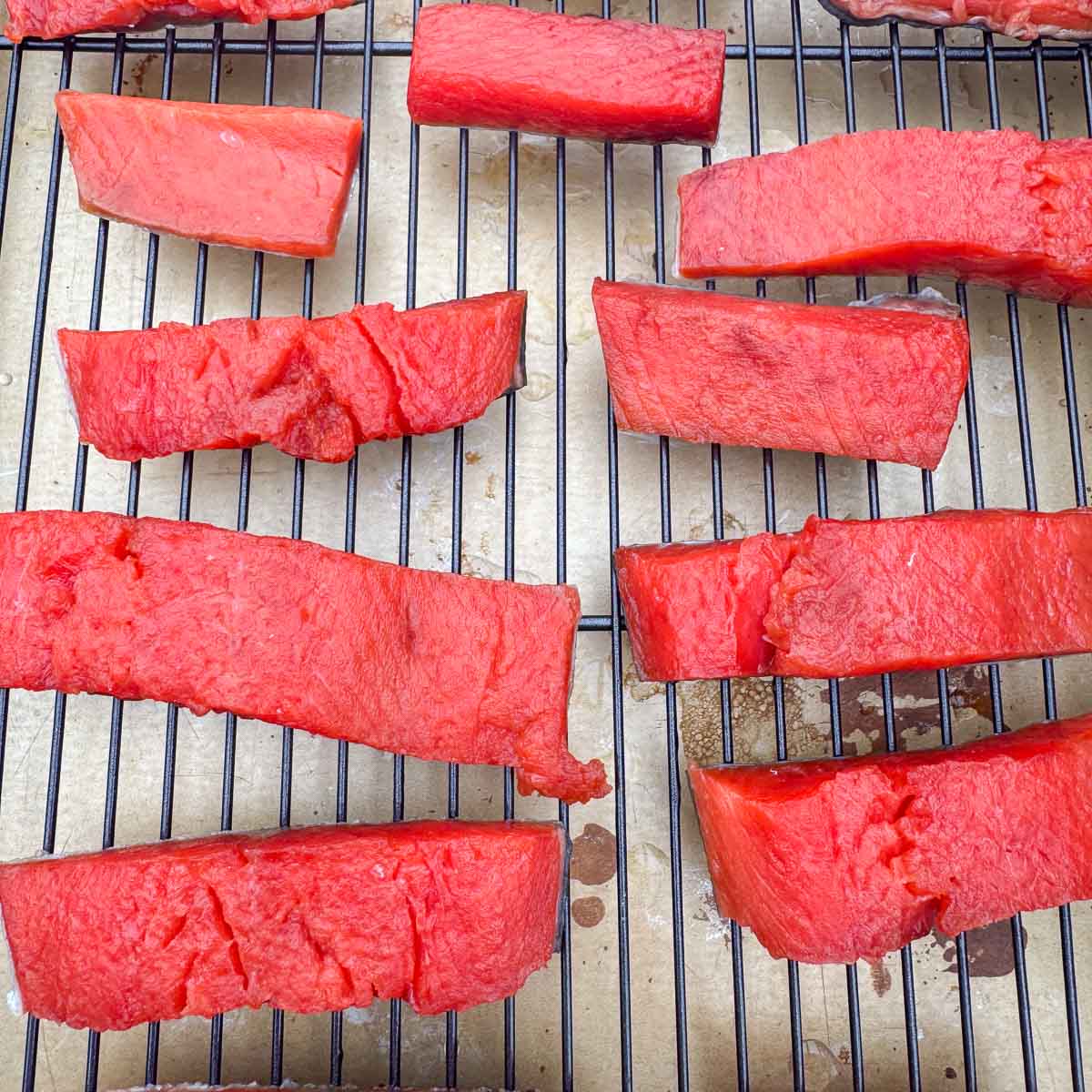 salmon strips drying on a rack over a tray