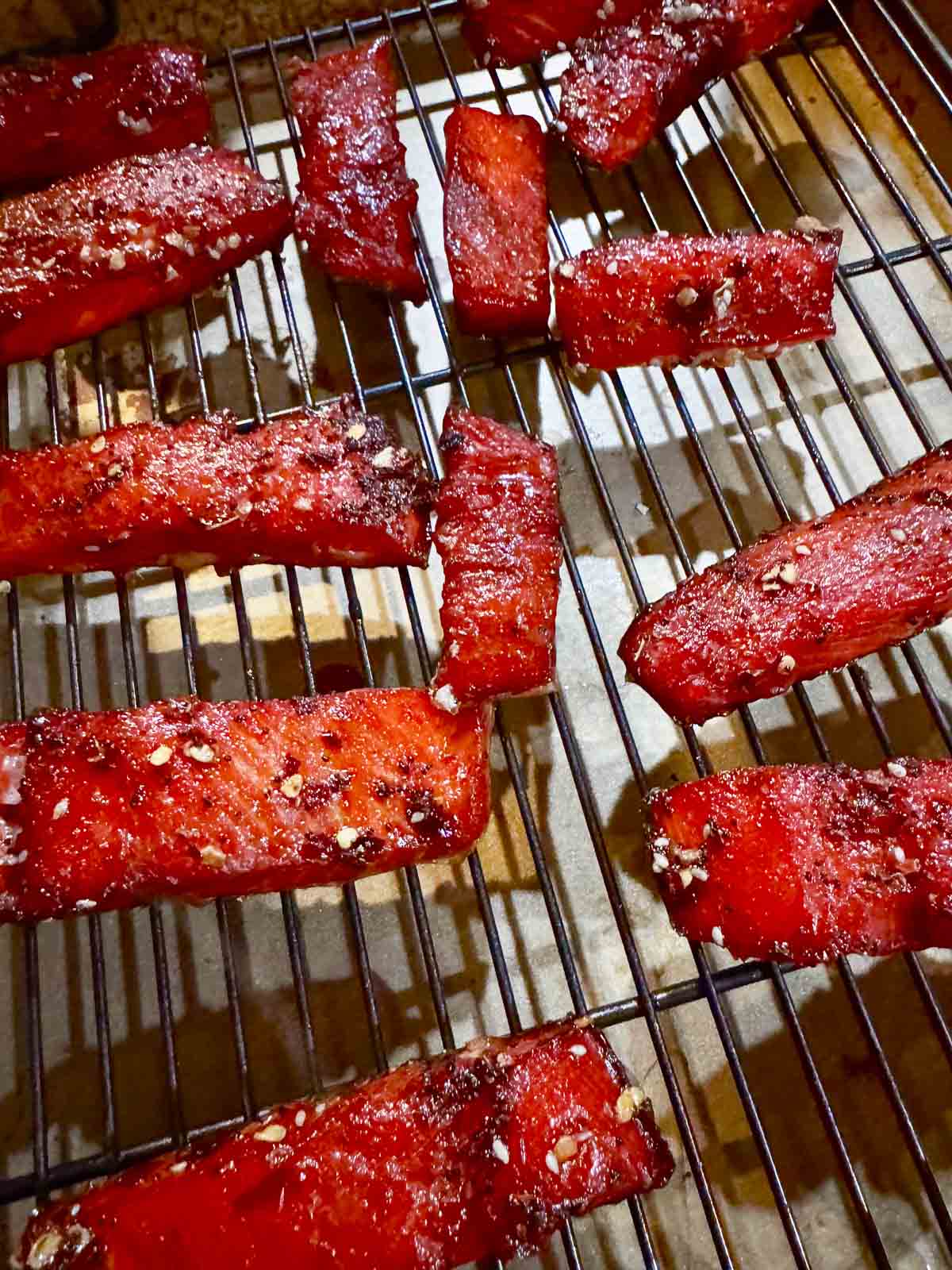 smoked candied salmon strips on a rack over a tray