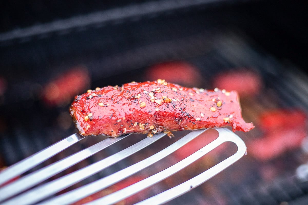 candied smoked salmon on a spatula over the grill