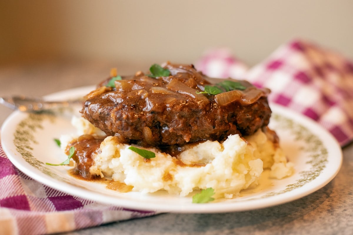 Salisbury steak on mashed potatoes on a checkered towel