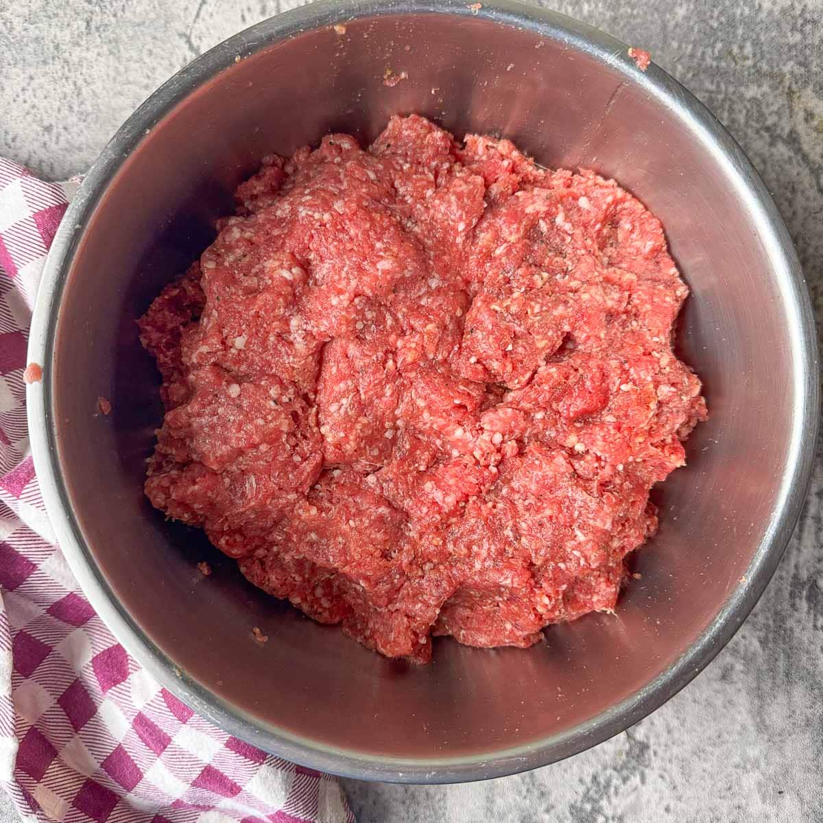 Salisbury steak beef mixture in a silver bowl