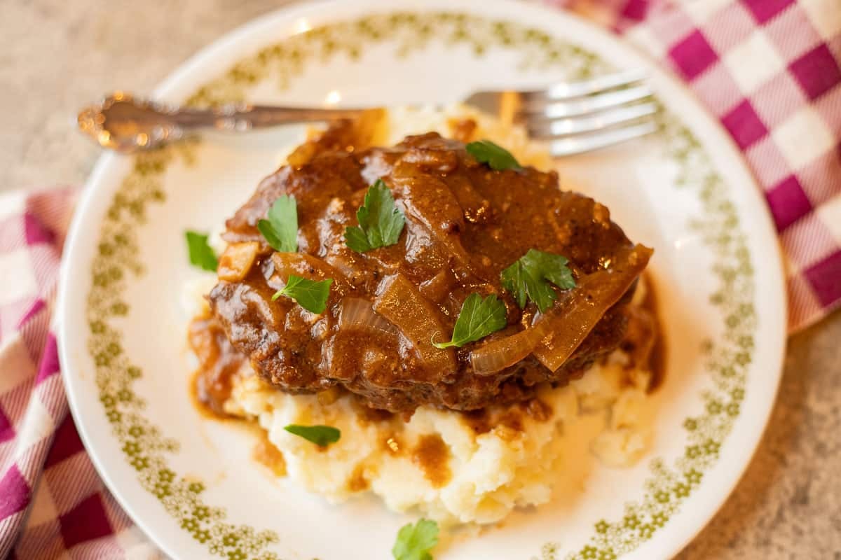 Salisbury steak over mashed potatoes on a white plate