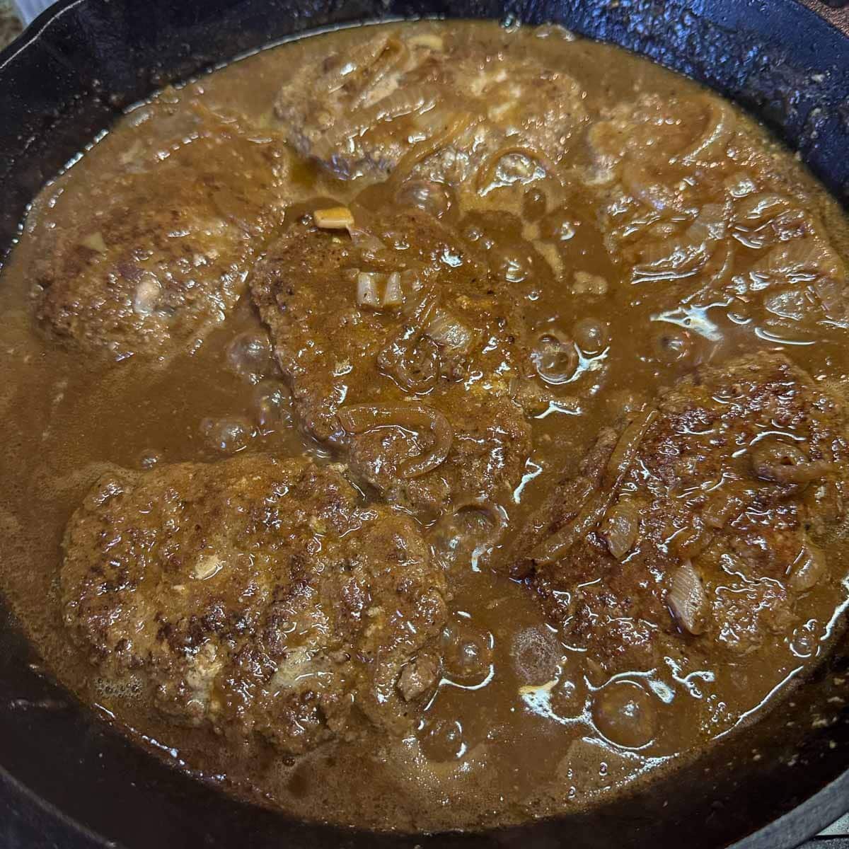 beef patties cooking in sauce