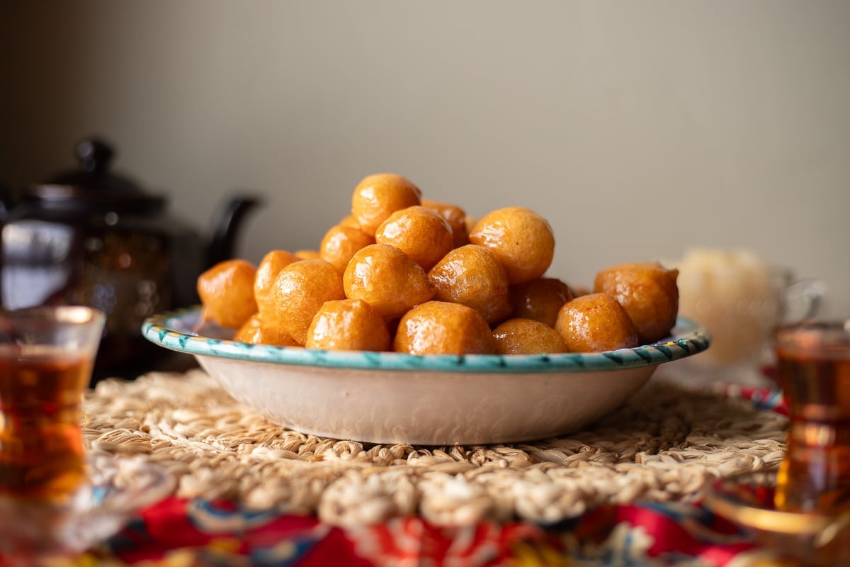 a bowl of luqaimat with a tea pot and tea cups