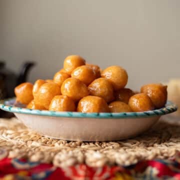 luqaimat in a bowl with tea pot behind it