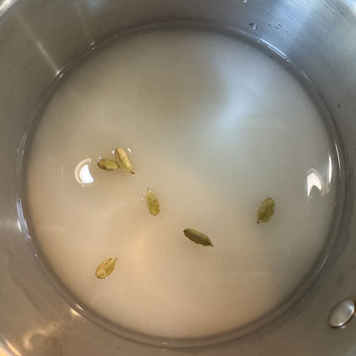 syrup ingredients including cardamom pods in a pot