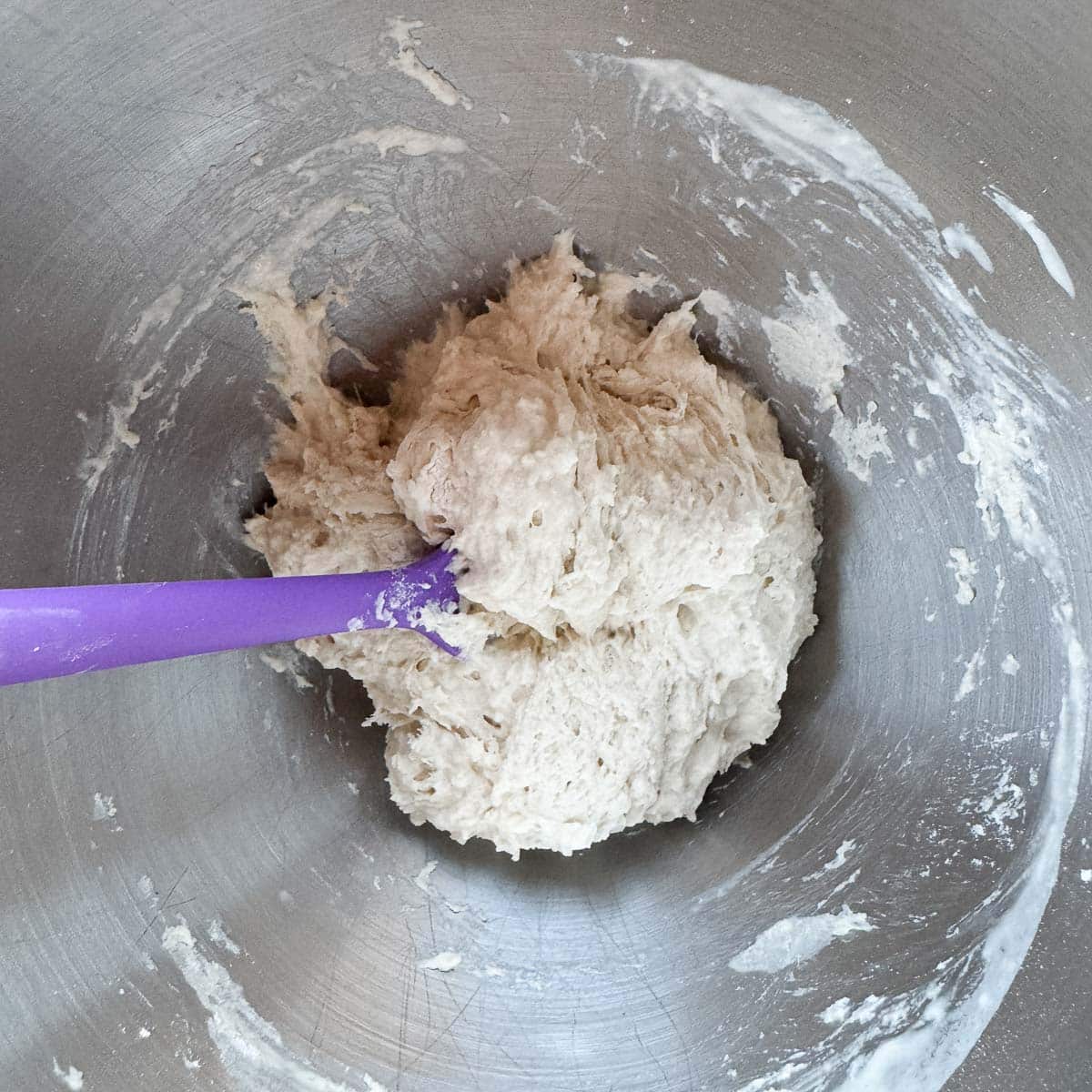 lokma dough in a mixing bowl with a purple rubber spatula