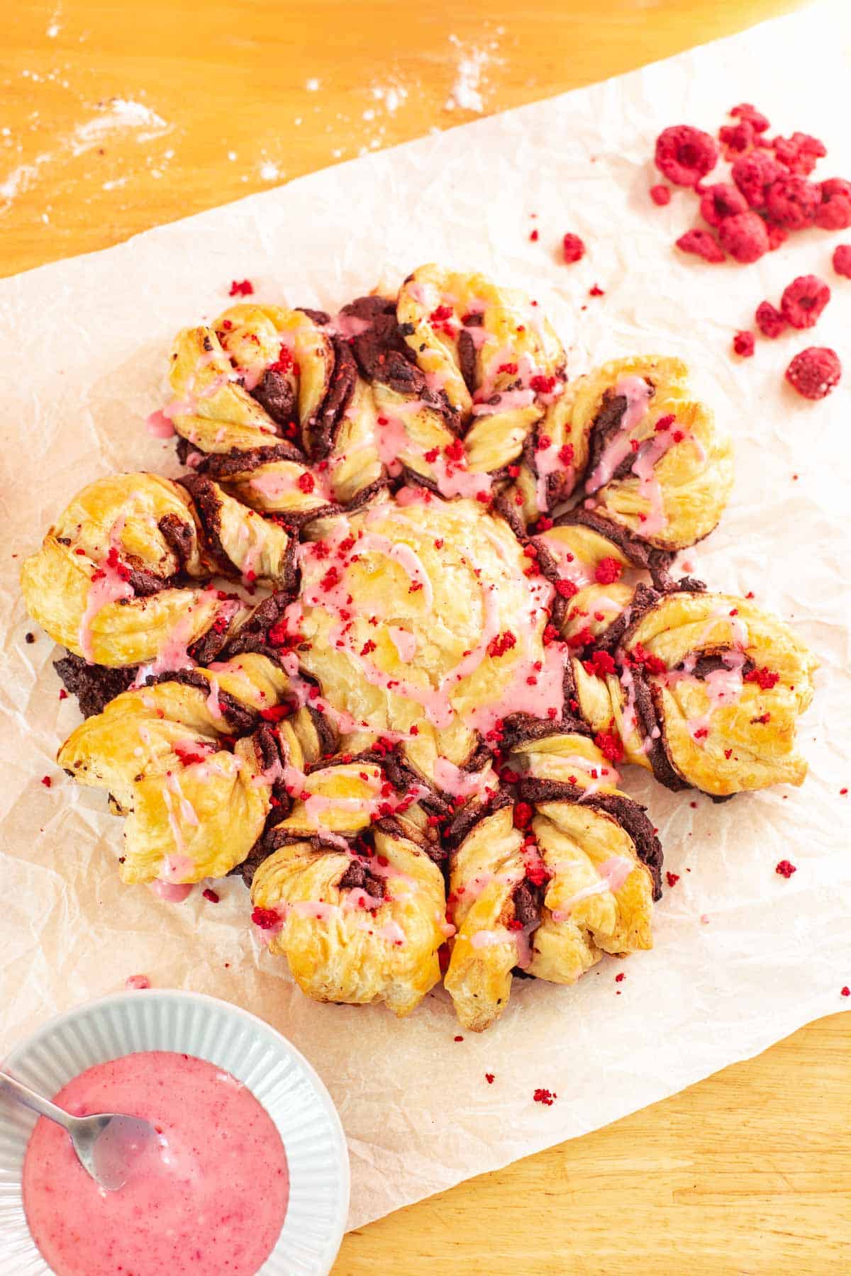 snowflake-shaped chocolate pastries with chocolate, freeze-dried raspberries, and raspberry glaze.
