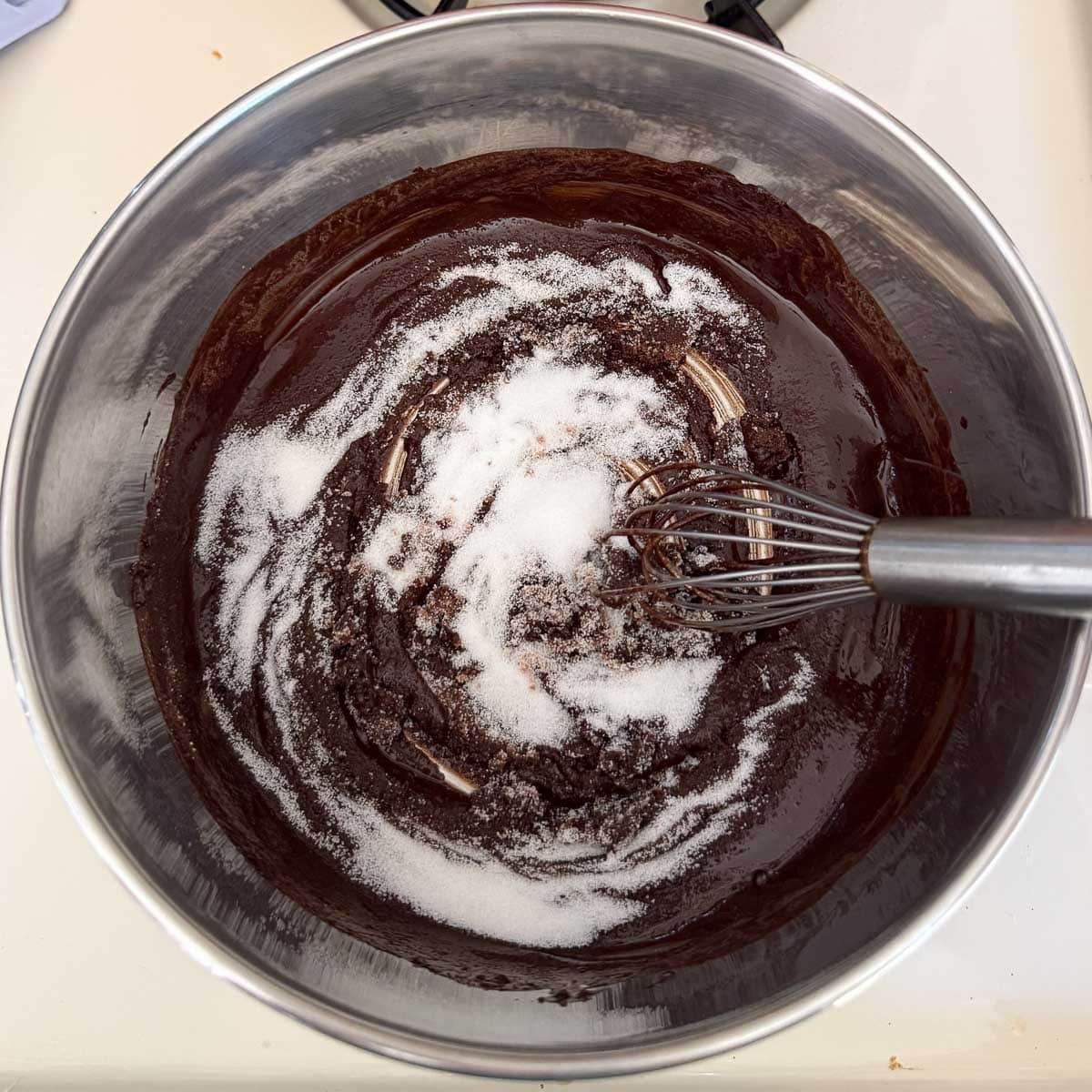 sugar being whisked into chocolate sauce.