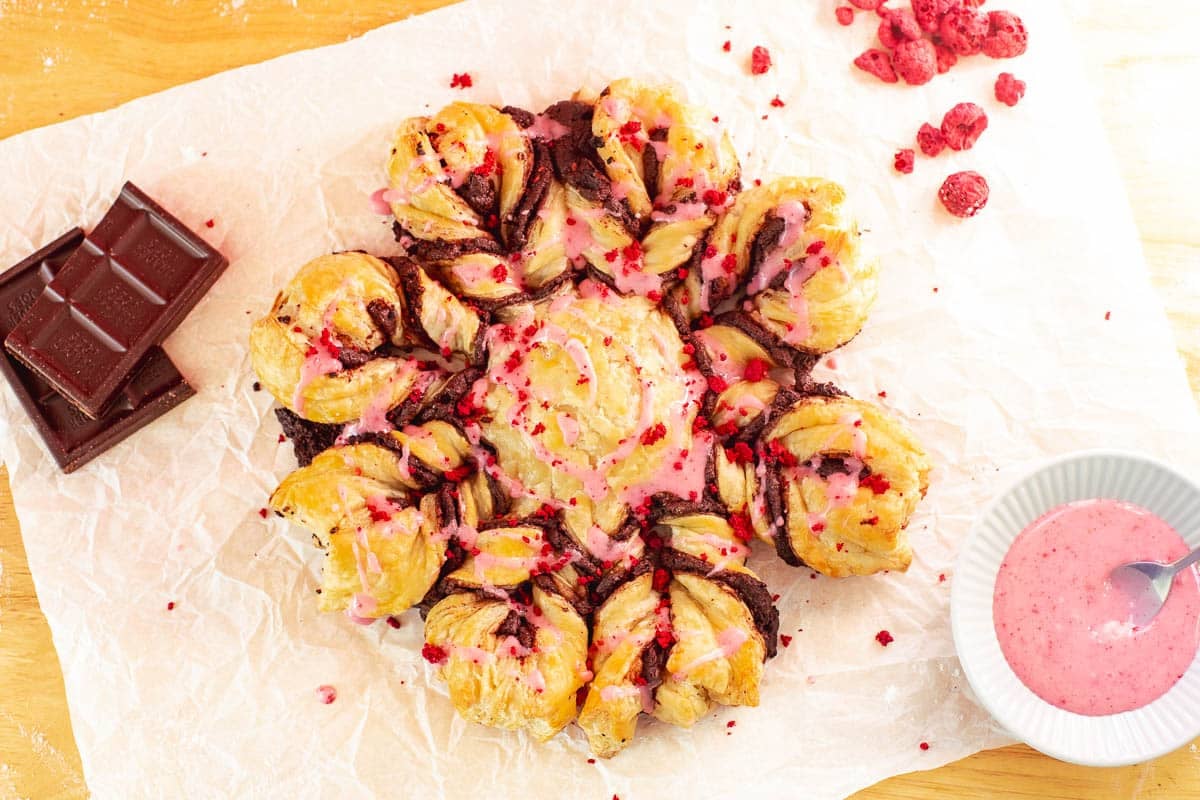 snowflake-shaped chocolate puff pastry with chocolate, freeze-dried raspberries, and raspberry glaze.