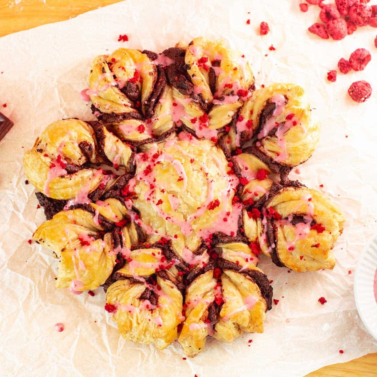 snowflake-shaped chocolate puff pastry with chocolate, freeze-dried raspberries, and raspberry glaze.