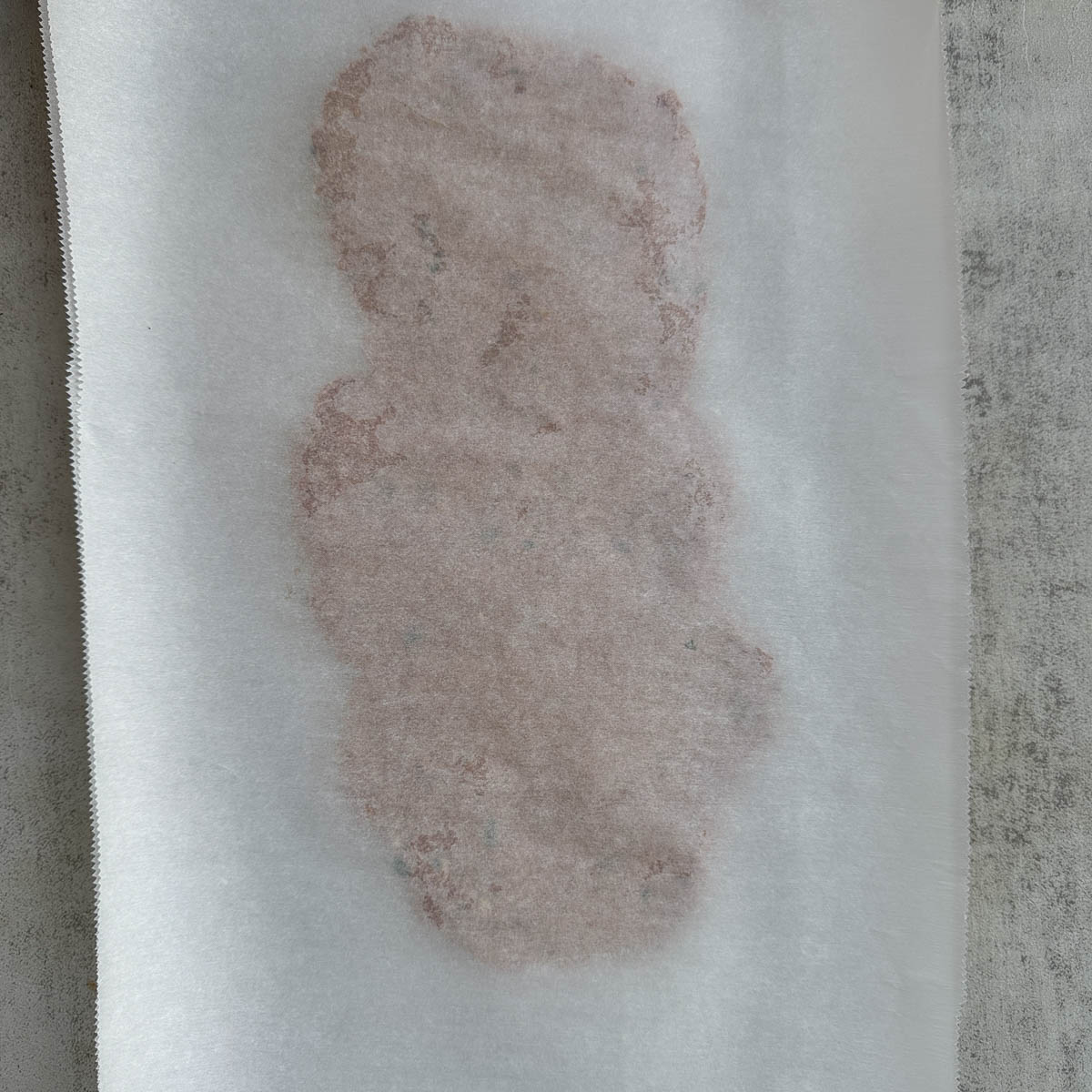 doner kebab meat mixture flattened between two sheets of parchment