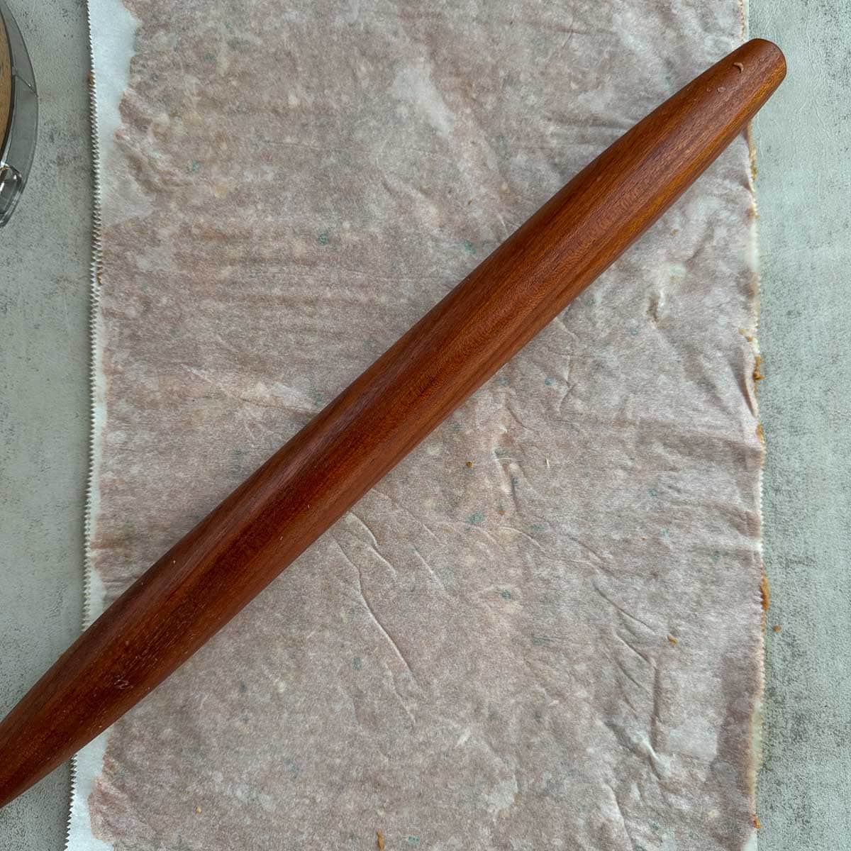 doner kebab meat rolled into a thin sheet between parchment paper with a rolling pin on top