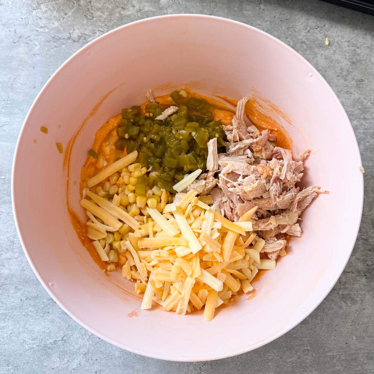 cheese, chicken, and veggies in bowl before mixing.