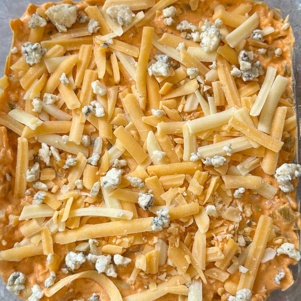 cheese layered over buffalo chicken dip with franks red.