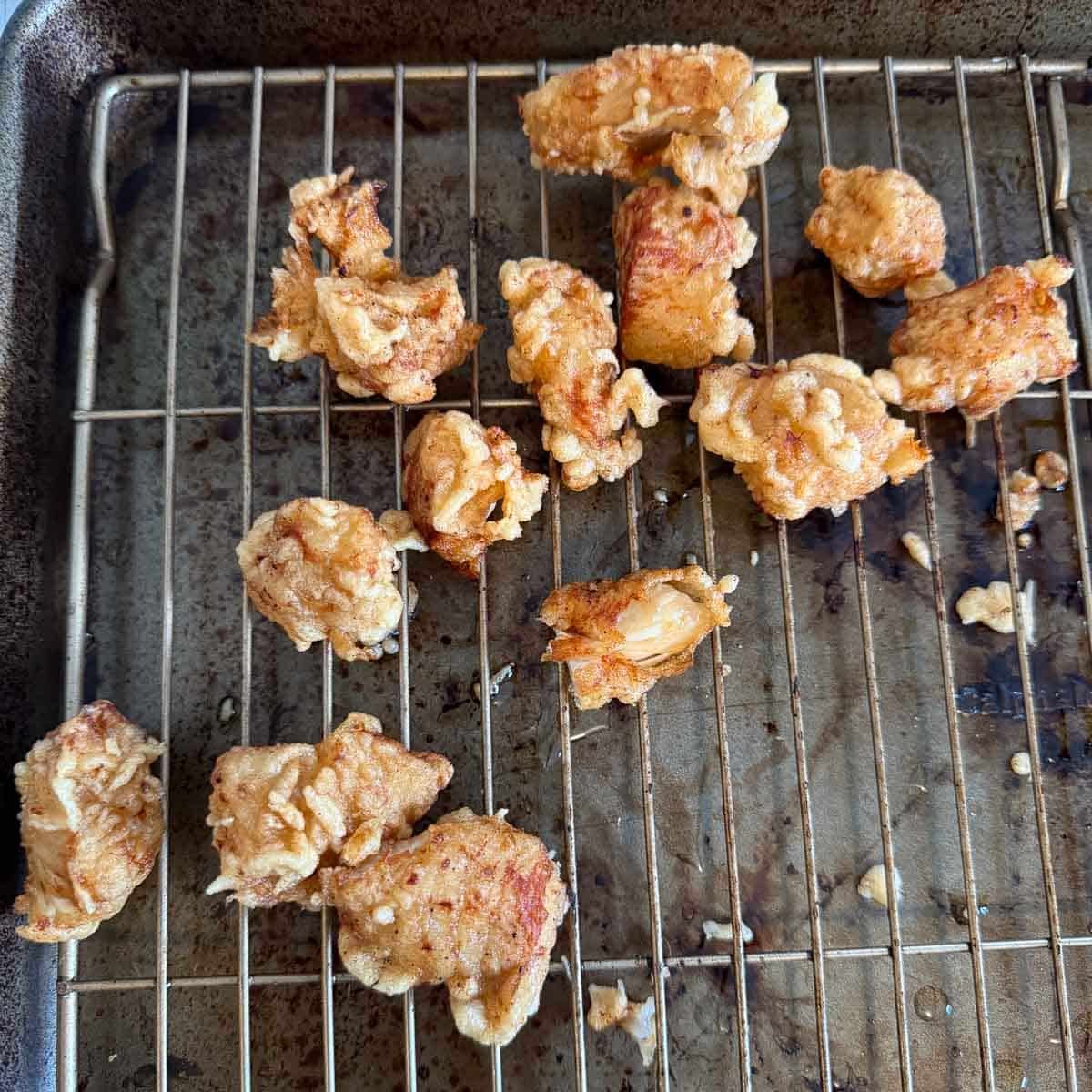 deep fried chicken draining on wire rack.