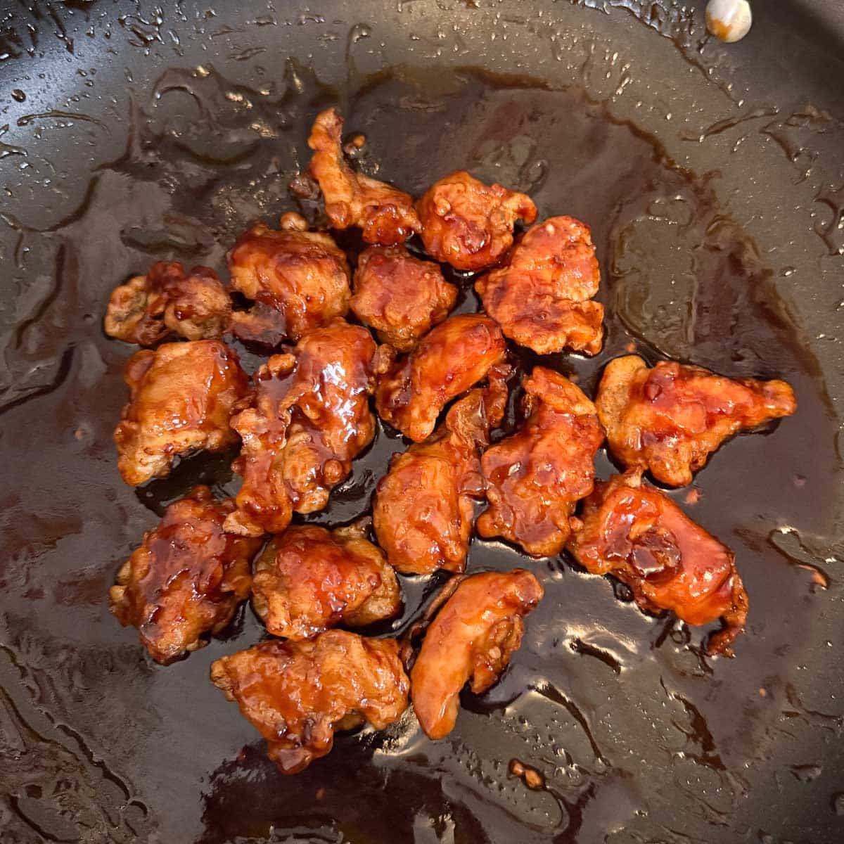 sticky sesame chicken after coating in pan.
