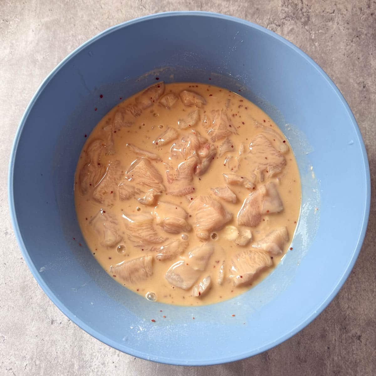 coated chicken pieces in bowl of batter.