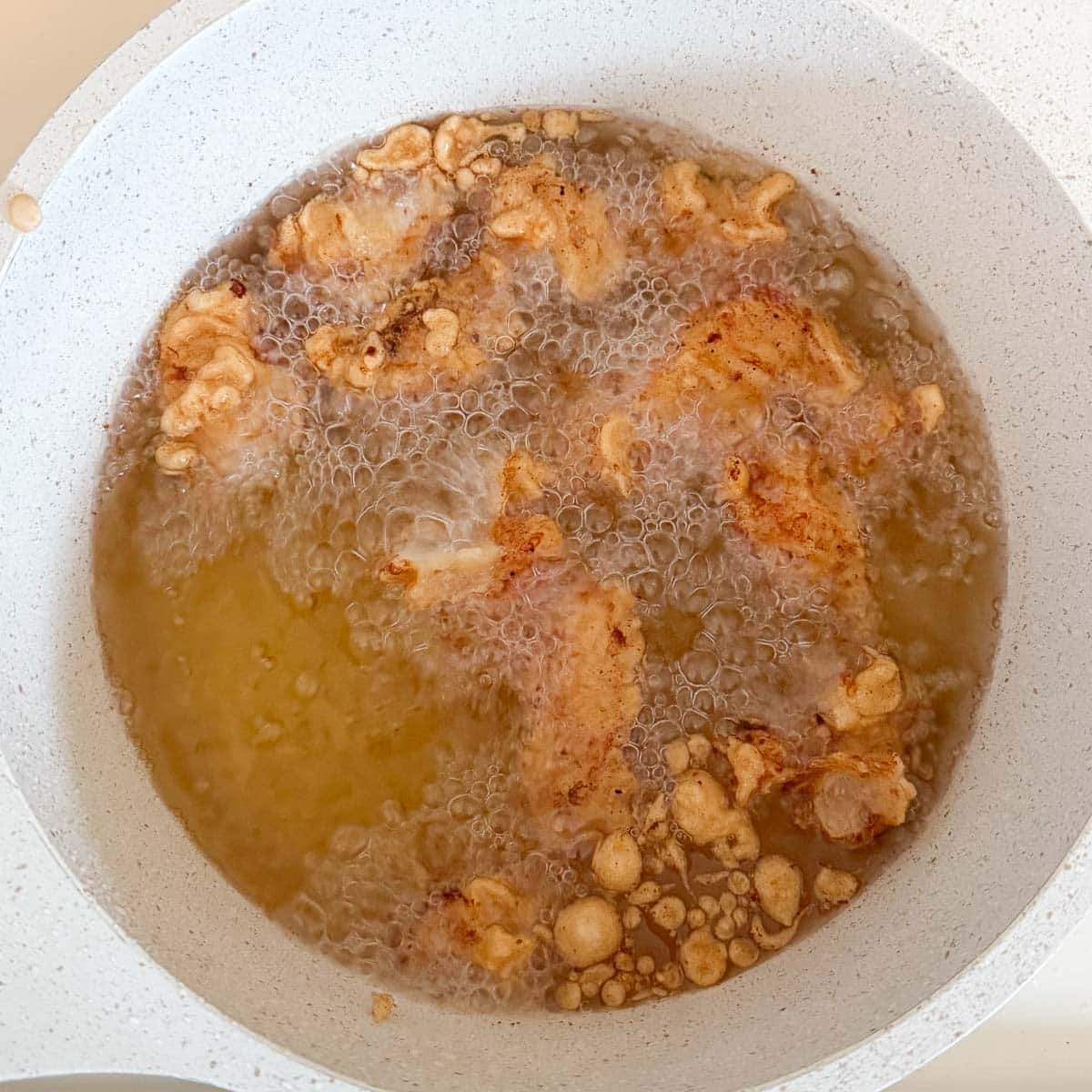 chicken pieces deep frying in oil.