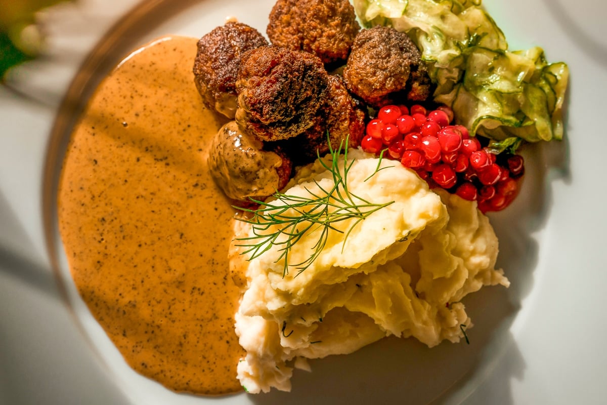 espagnole brown sauce on plate beside mashed potatoes, meatballs, and pickled veggies.