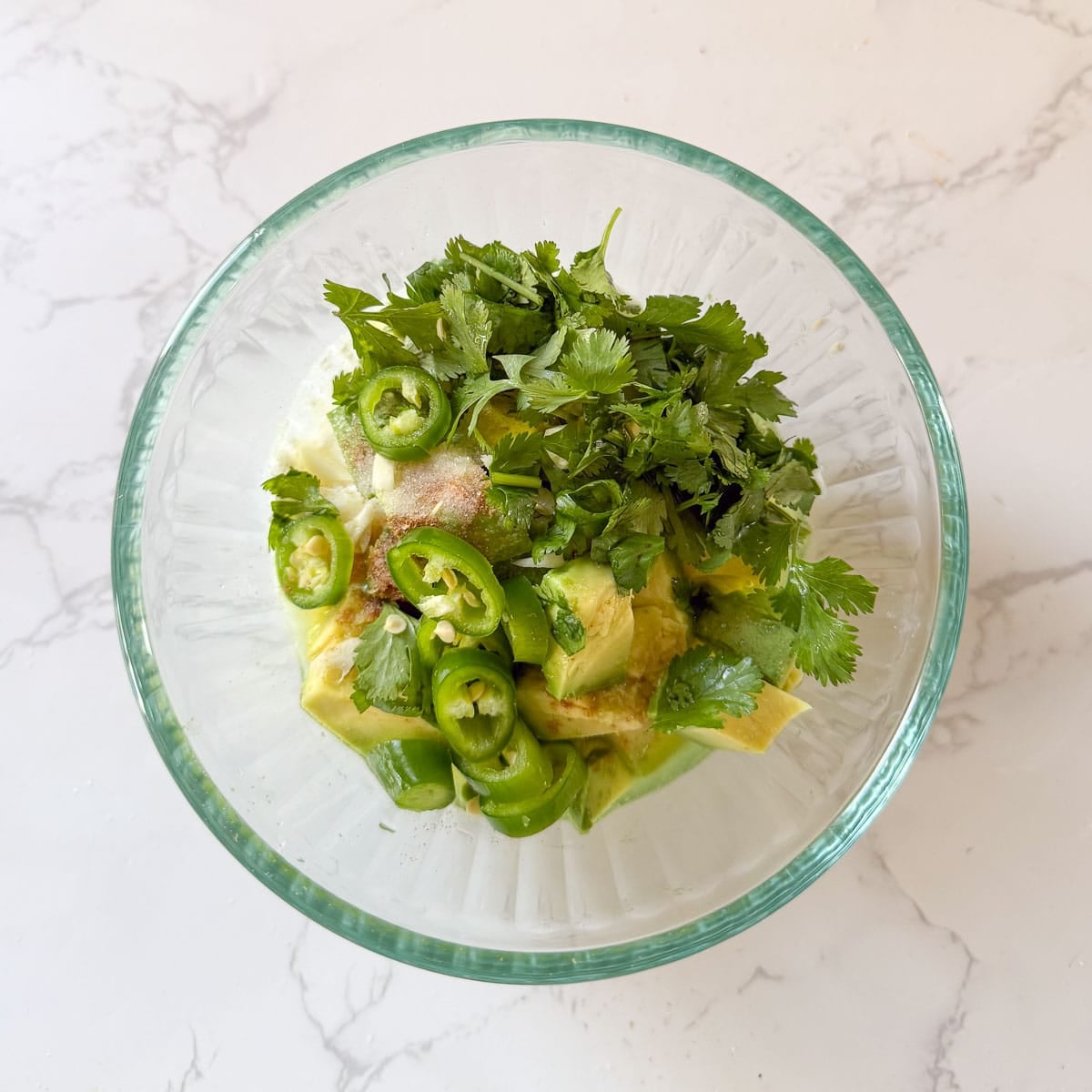 avocados, cilantro, jalapeons and spices in a bowl before blending.