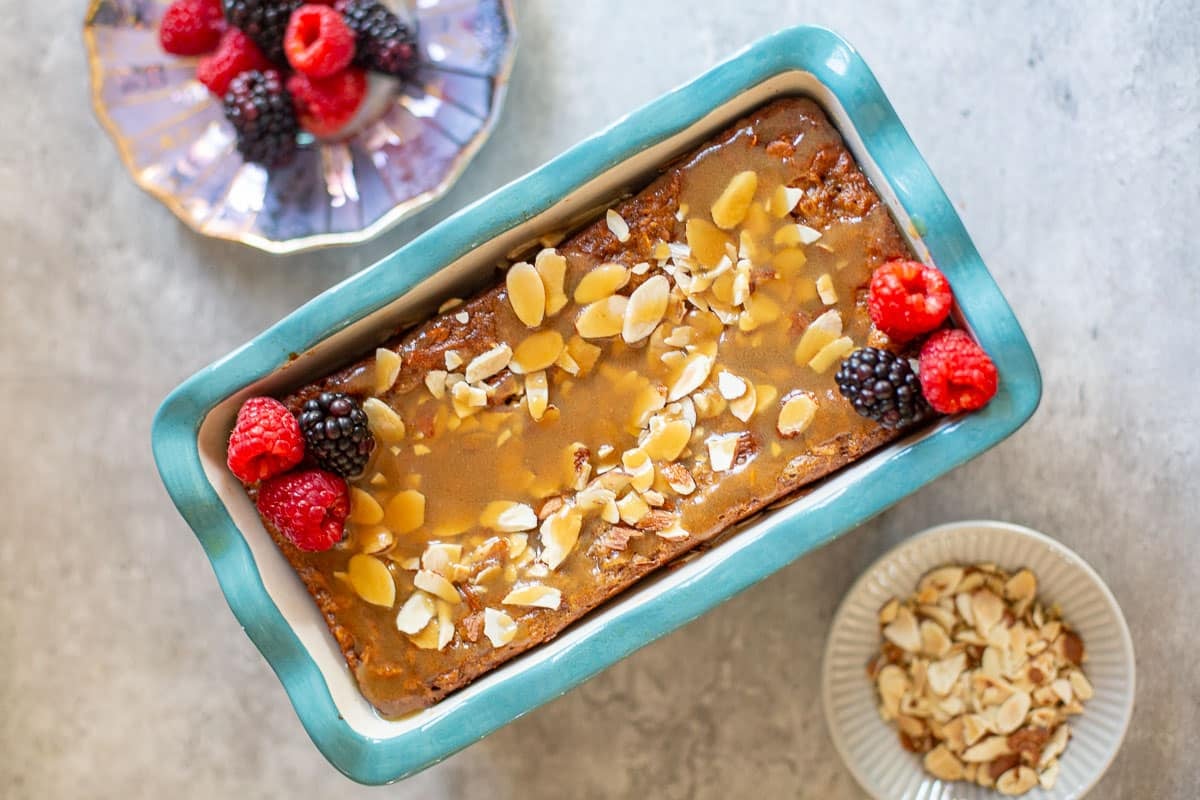 high protein baked oats in loaf pan with almonds and fresh berries.