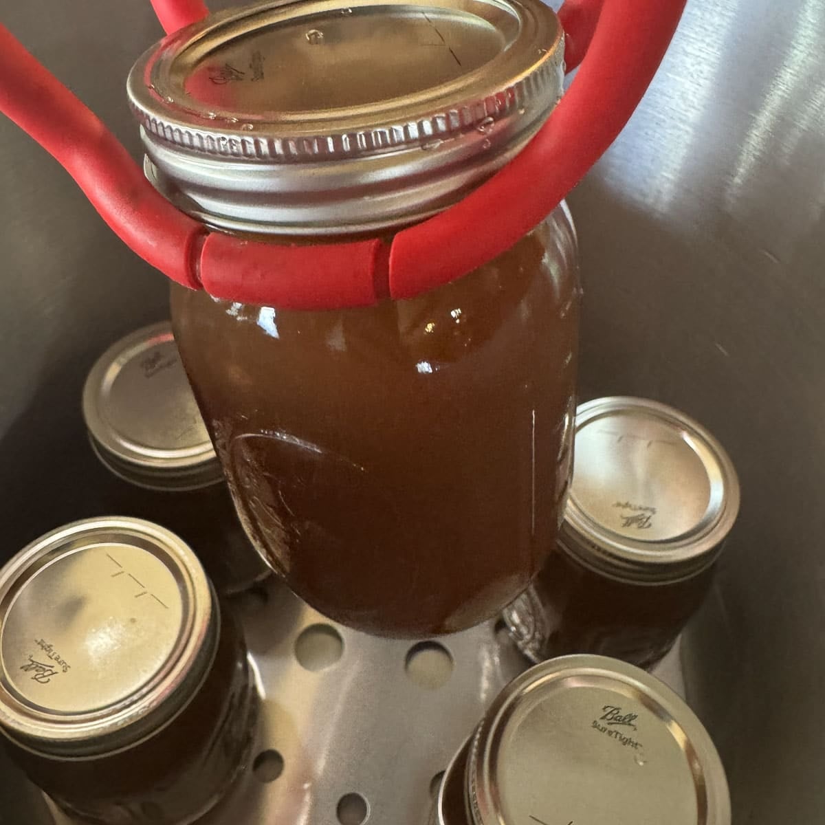 removing jars of beef bone broth from a pressure cooker