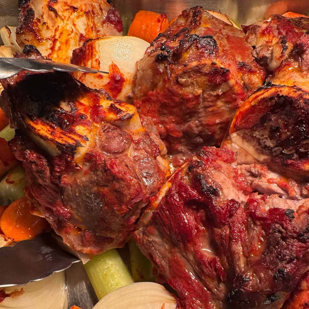 roasted beef bones and veggies being turned with tongs