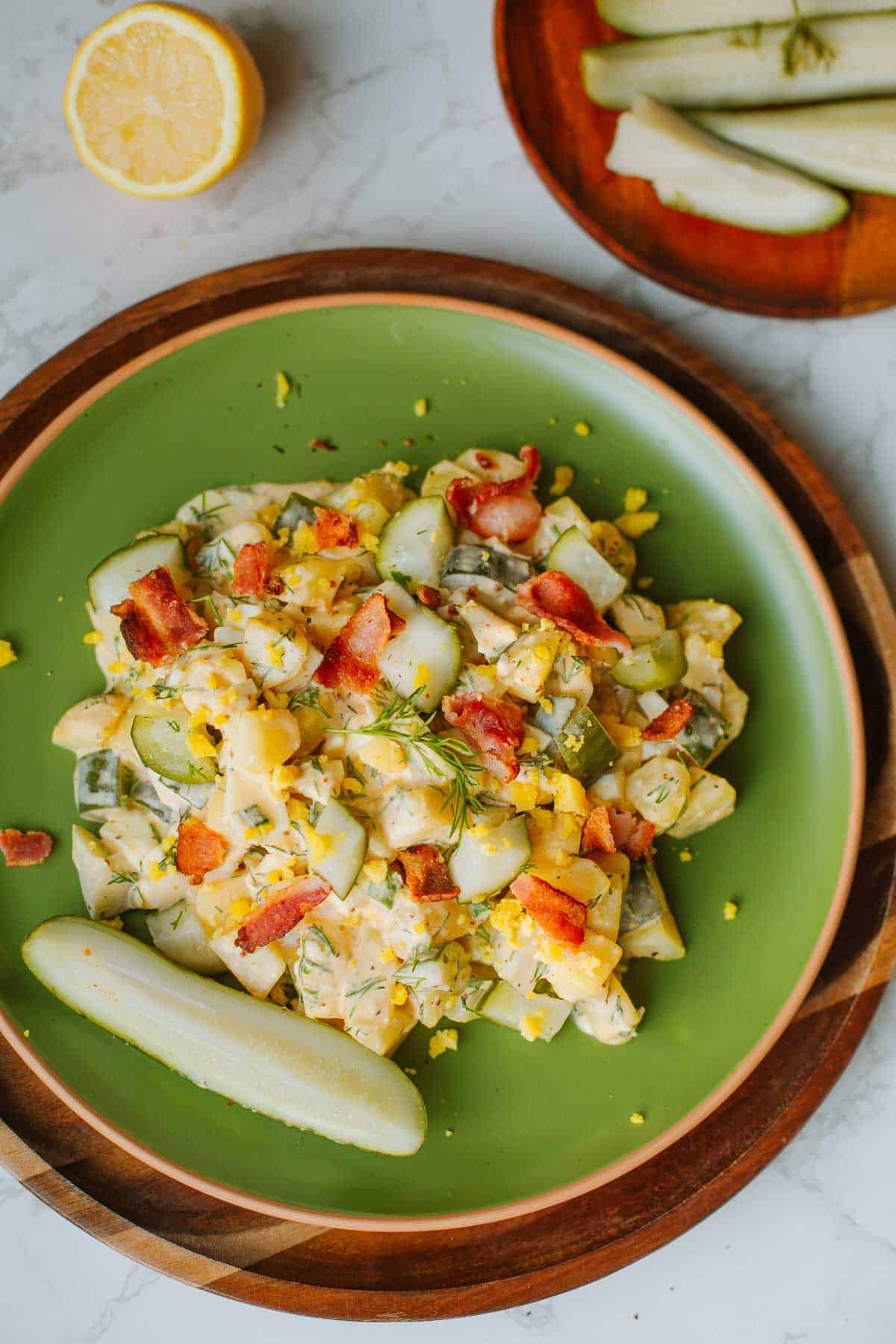 dill pickle potato salad on a green plate with a pickle