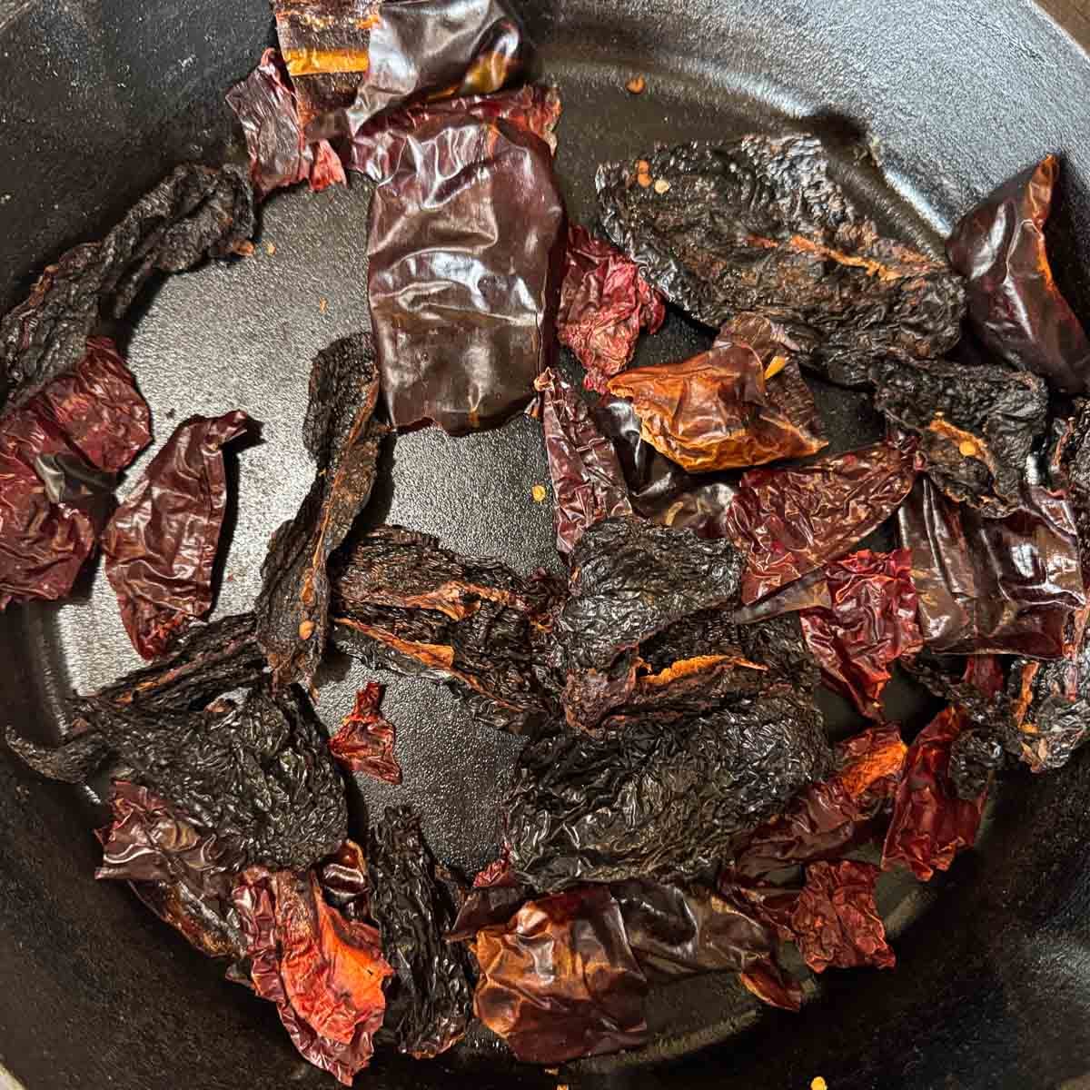 dried chiles being charred in a pan