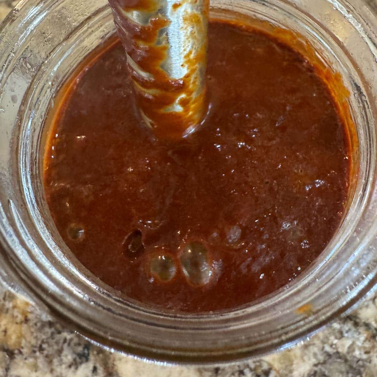 chile sauce in a cup with an immersion blender