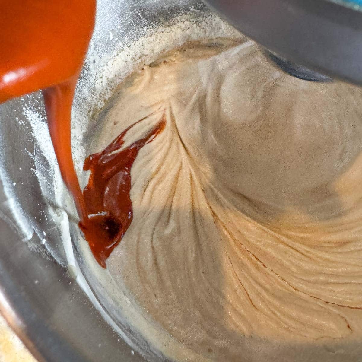 adding chile sauce to whipped lard in a mixer